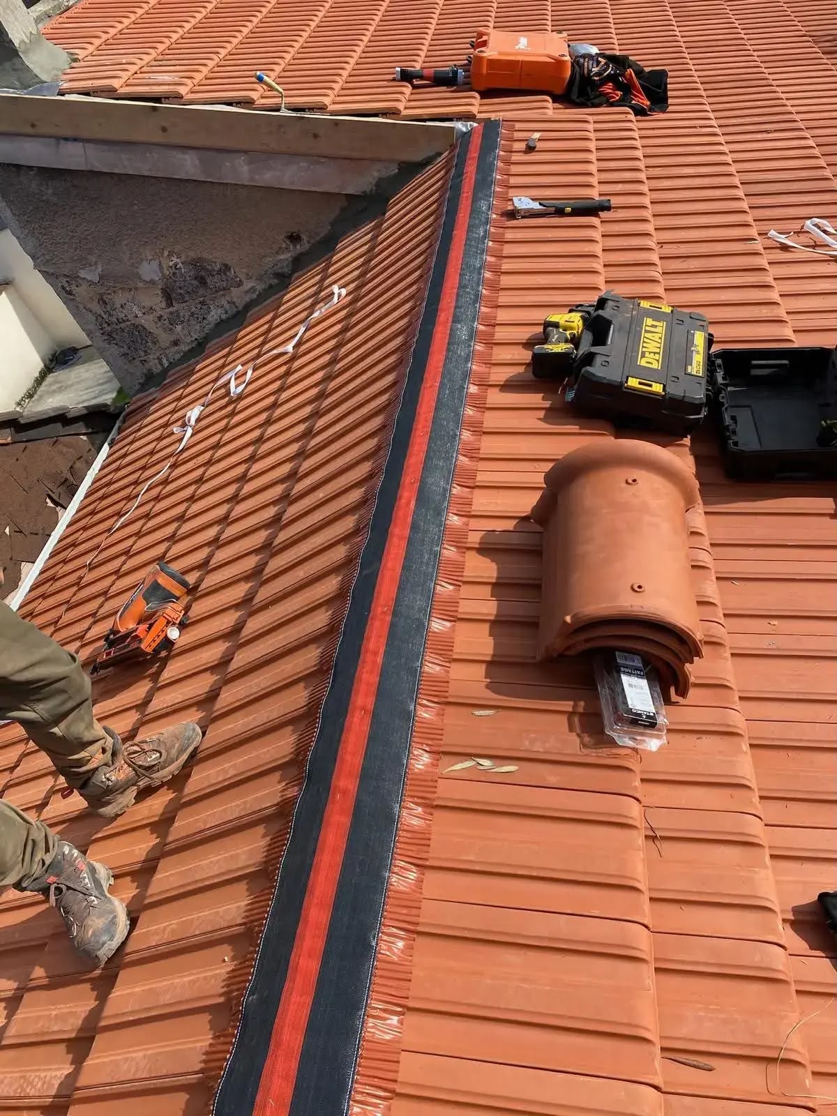 Pose de tuiles neuves avec closoir de faîtage ventilé sur un chantier de couverture